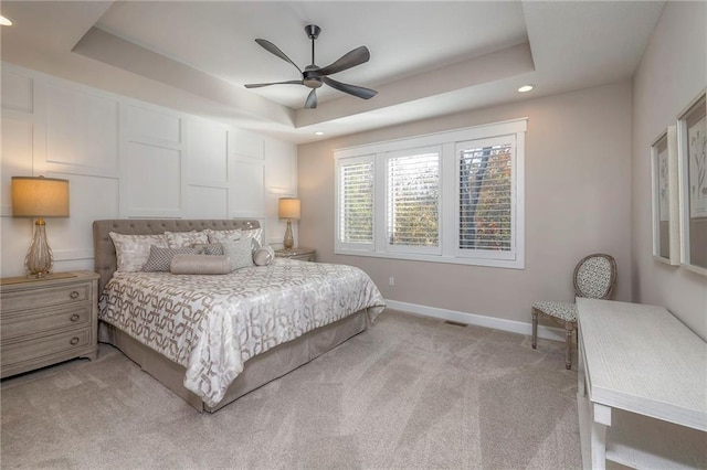 bedroom featuring ceiling fan, a raised ceiling, and light colored carpet