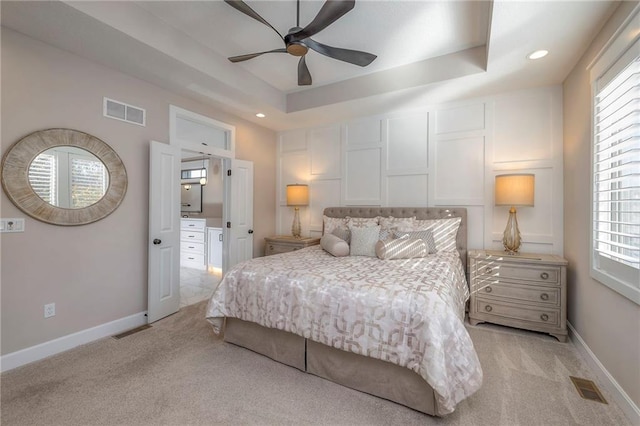 carpeted bedroom featuring ceiling fan, multiple windows, and a tray ceiling