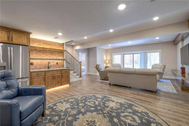 living room featuring a textured ceiling, wooden walls, light wood-type flooring, and sink