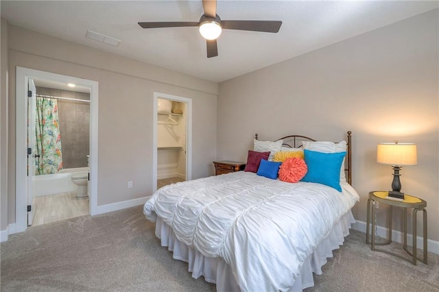 carpeted bedroom with connected bathroom, ceiling fan, a walk in closet, and a closet