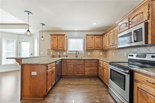 kitchen featuring kitchen peninsula, dark hardwood / wood-style flooring, light stone countertops, and appliances with stainless steel finishes