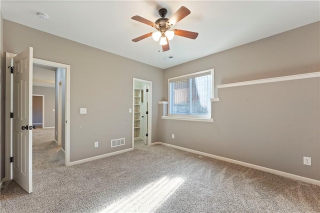 unfurnished bedroom with ceiling fan, light carpet, a closet, and a walk in closet