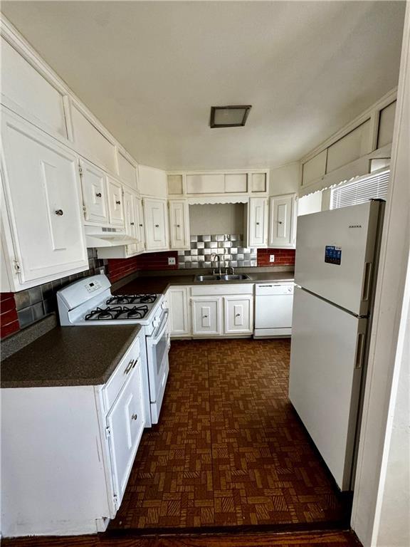 kitchen featuring white appliances, dark parquet floors, decorative backsplash, white cabinets, and sink