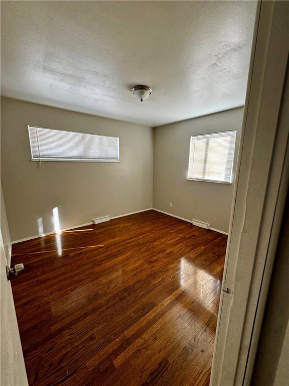 unfurnished room with a textured ceiling and dark wood-type flooring