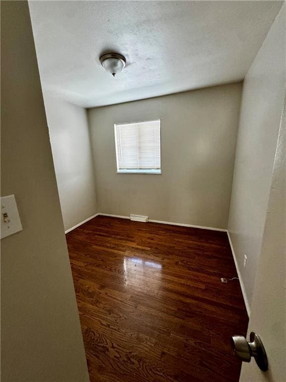 spare room with dark wood-type flooring and a textured ceiling