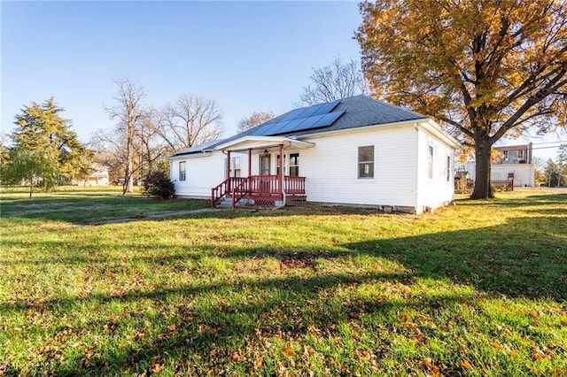 back of property featuring solar panels and a yard