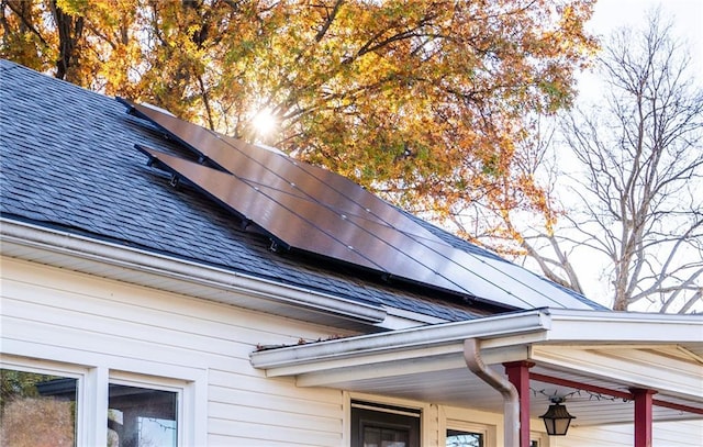 exterior details with a shingled roof, gutters, and a downspout