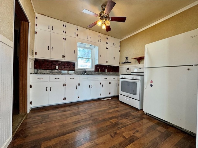 kitchen with white appliances, dark wood finished floors, dark countertops, white cabinetry, and a sink