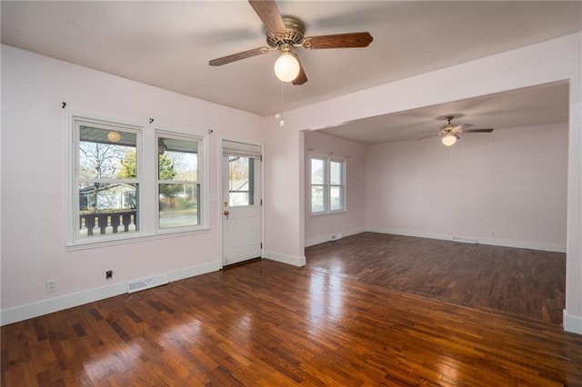 spare room with a ceiling fan, baseboards, visible vents, and dark wood-style flooring