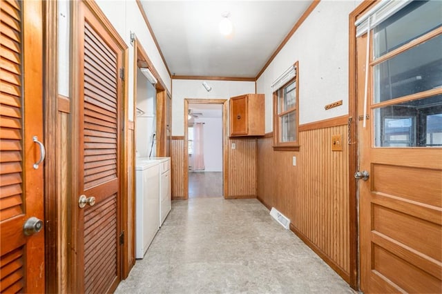 corridor featuring wooden walls, visible vents, wainscoting, ornamental molding, and separate washer and dryer