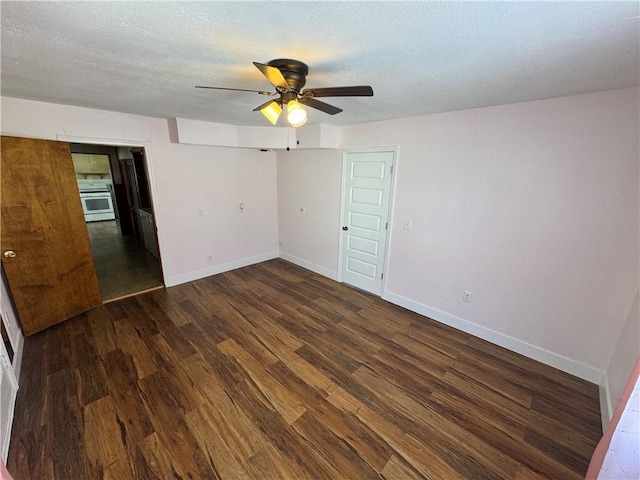 spare room featuring a textured ceiling, ceiling fan, dark wood-type flooring, and baseboards