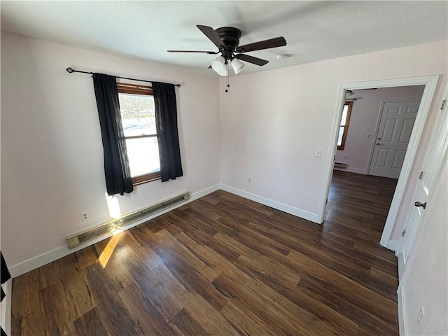 unfurnished room featuring dark wood-style floors, baseboard heating, a ceiling fan, and baseboards