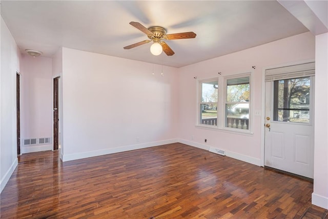 unfurnished room featuring dark wood-type flooring, visible vents, and baseboards