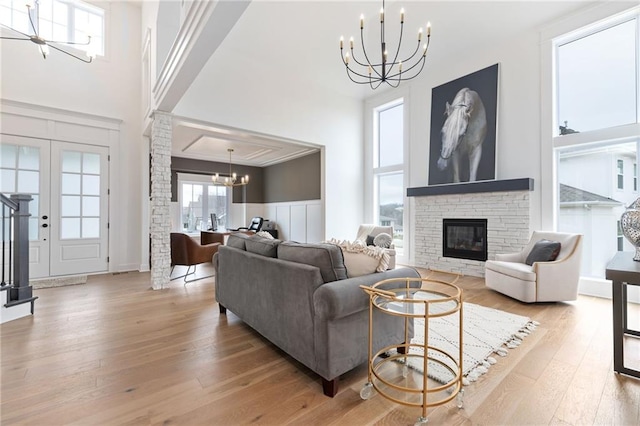 living room with a high ceiling, crown molding, light hardwood / wood-style floors, and a fireplace