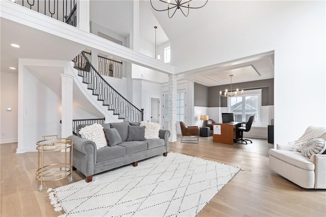 living room with a high ceiling, light wood-type flooring, and a chandelier