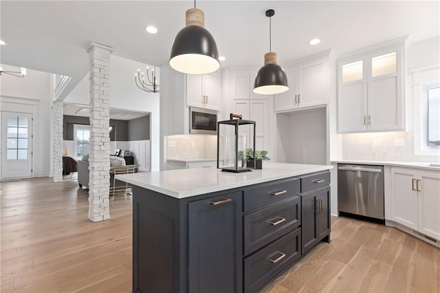 kitchen featuring ornate columns, white cabinets, light hardwood / wood-style flooring, appliances with stainless steel finishes, and decorative light fixtures