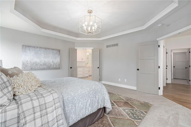 bedroom with a chandelier, ensuite bath, a raised ceiling, and carpet