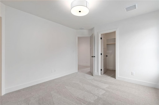 unfurnished bedroom with a closet, a spacious closet, and light colored carpet