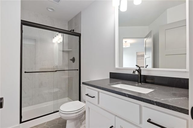 bathroom with toilet, vanity, tile patterned flooring, and a shower with shower door