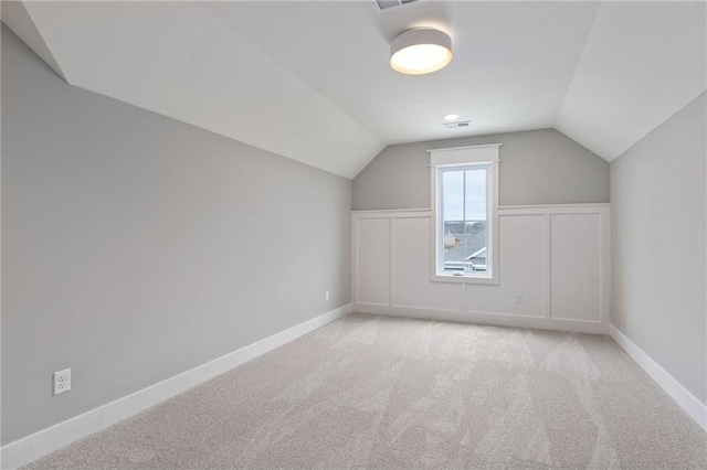 additional living space featuring light carpet and vaulted ceiling