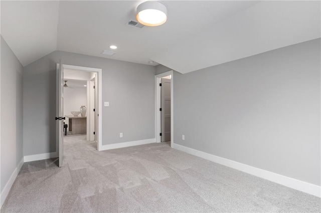 additional living space featuring light colored carpet and vaulted ceiling