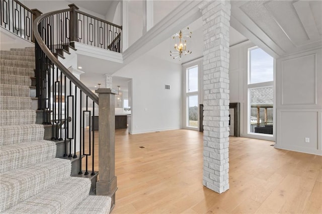 foyer with a towering ceiling, light hardwood / wood-style floors, and decorative columns