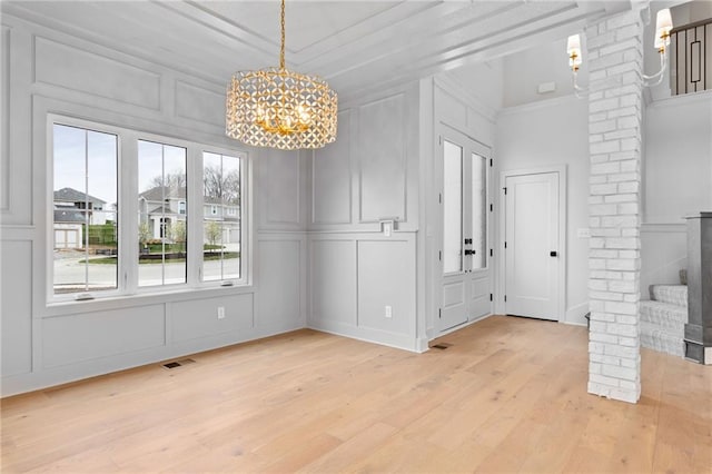 unfurnished dining area featuring light hardwood / wood-style floors, crown molding, and decorative columns