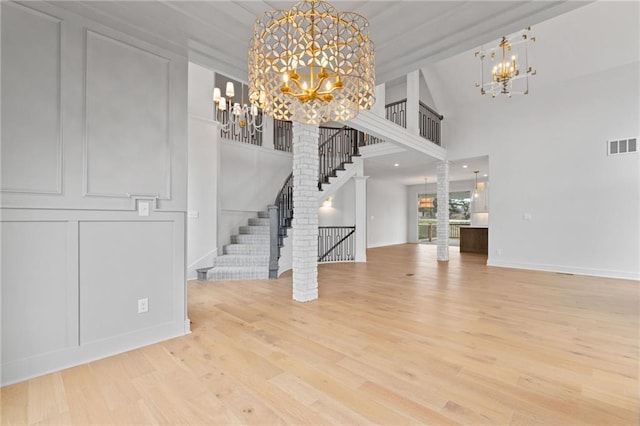 unfurnished living room with high vaulted ceiling, hardwood / wood-style flooring, and a notable chandelier