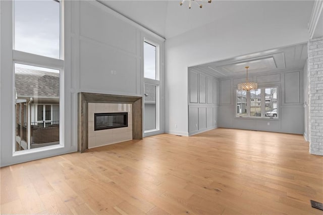 unfurnished living room with a chandelier, light hardwood / wood-style floors, and brick wall