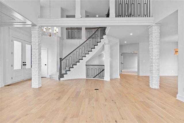 entrance foyer with french doors, light hardwood / wood-style floors, a high ceiling, and decorative columns