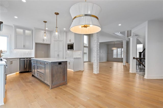 kitchen featuring plenty of natural light, light wood-type flooring, ornate columns, and stainless steel appliances