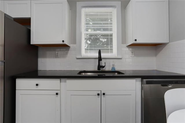 6206 Harrison St, Kansas City, MO 64110 - kitchen featuring stainless steel dishwasher, a sink, dark countertops, and white cabinetry