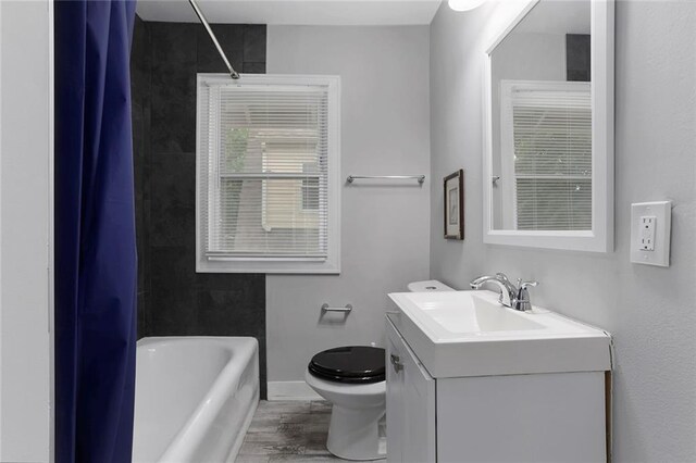 6206 Harrison St, Kansas City, MO 64110 - bathroom featuring wood finished floors, toilet, vanity, shower / bath combo, and baseboards