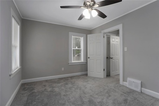 unfurnished bedroom featuring multiple windows, light colored carpet, ceiling fan, and crown molding