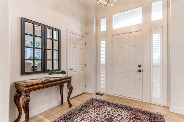 foyer featuring plenty of natural light, wood-type flooring, and an inviting chandelier