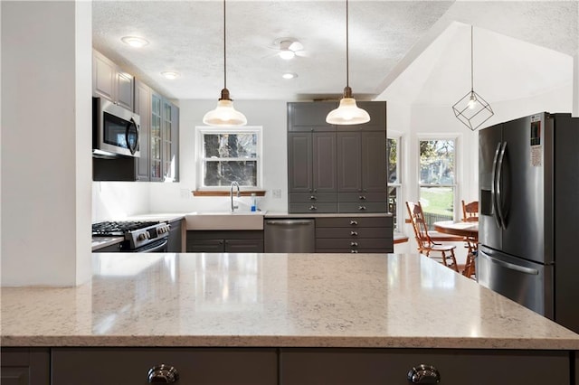 kitchen featuring light stone counters, appliances with stainless steel finishes, a textured ceiling, gray cabinetry, and pendant lighting