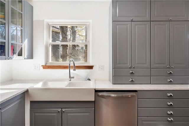 bar with light stone countertops, gray cabinetry, sink, and dishwasher