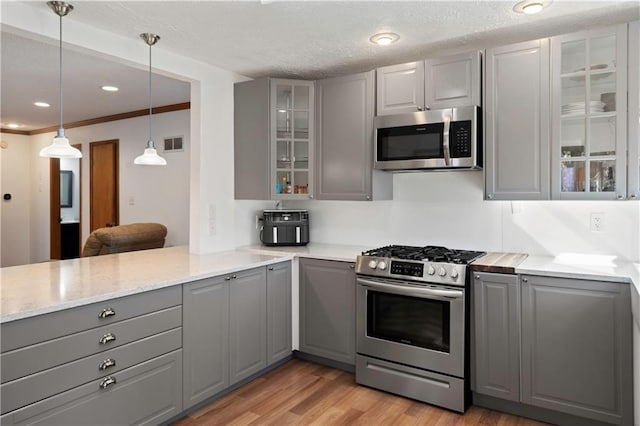 kitchen featuring stainless steel appliances, light hardwood / wood-style floors, decorative light fixtures, crown molding, and gray cabinets