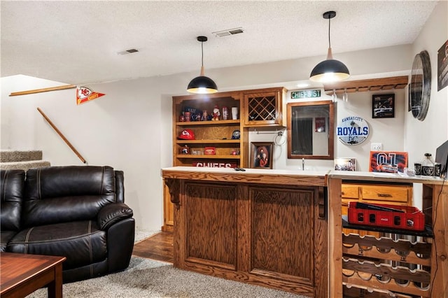 bar with hanging light fixtures, a textured ceiling, and carpet flooring