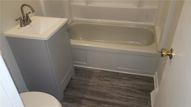 bathroom featuring a bathing tub, vanity, hardwood / wood-style flooring, and toilet