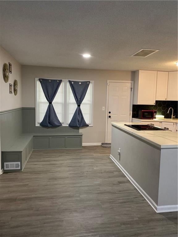 7714 E 110th St, Kansas City, MO 64134 - dining space featuring dark wood finished floors, plenty of natural light, wainscoting, and a textured ceiling