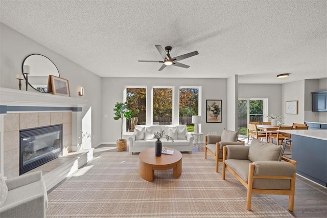 living room with a fireplace, hardwood / wood-style flooring, ceiling fan, and a textured ceiling