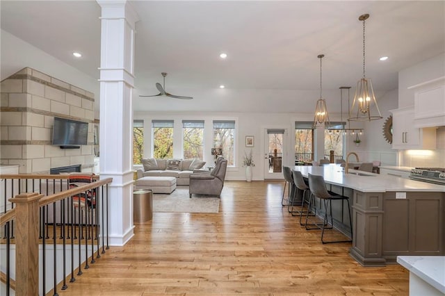 kitchen with hanging light fixtures, sink, light hardwood / wood-style flooring, and decorative columns