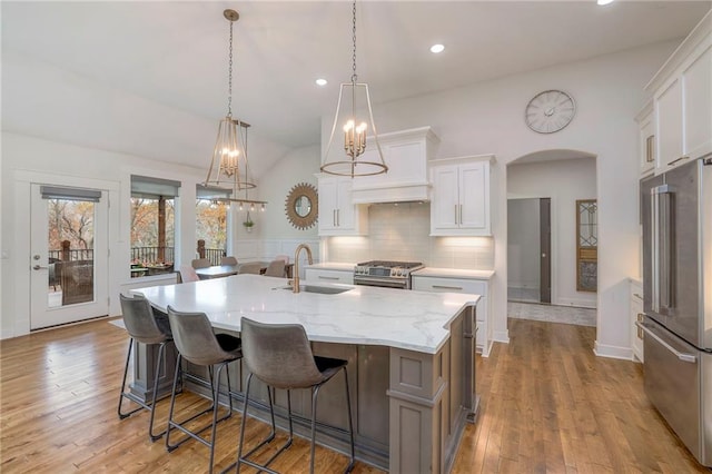 kitchen with stainless steel appliances, decorative light fixtures, sink, white cabinets, and a spacious island