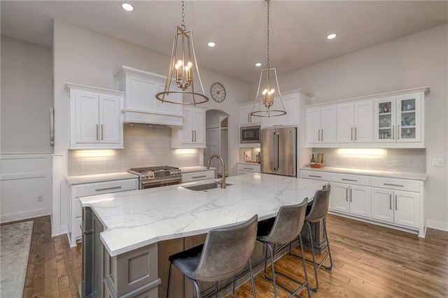 kitchen with an island with sink, premium appliances, and white cabinets