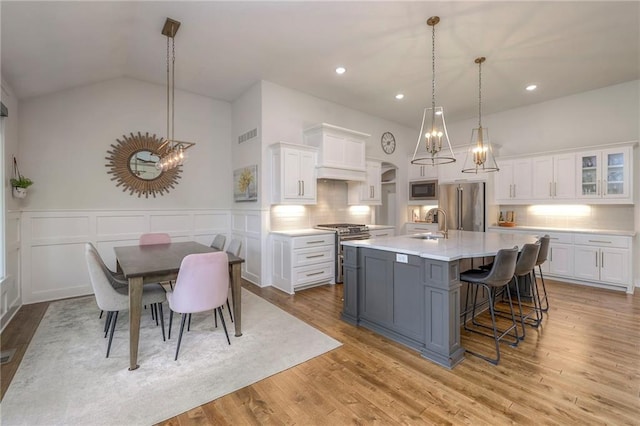 kitchen featuring light wood-type flooring, high end appliances, and white cabinets