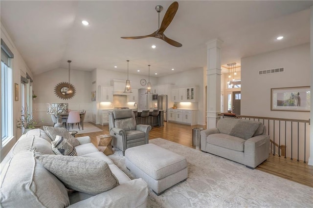 living room with ceiling fan, light hardwood / wood-style flooring, and vaulted ceiling