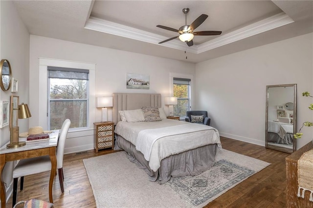 bedroom with a tray ceiling, multiple windows, ceiling fan, and dark hardwood / wood-style floors