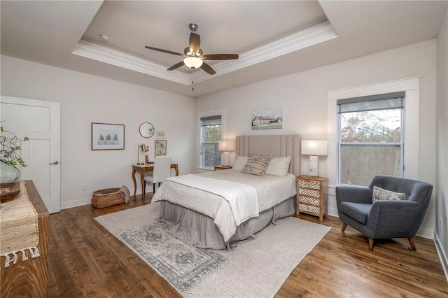 bedroom with hardwood / wood-style floors, ceiling fan, crown molding, and a tray ceiling