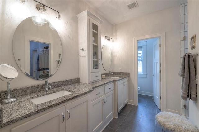 bathroom with toilet, vanity, and tile patterned floors